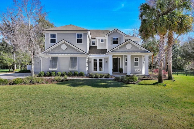 view of front facade featuring covered porch, driveway, a shingled roof, and a front lawn