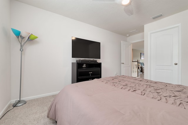 carpeted bedroom featuring ceiling fan and a textured ceiling