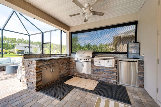 view of patio with an outdoor kitchen, ceiling fan, a lanai, and a grill