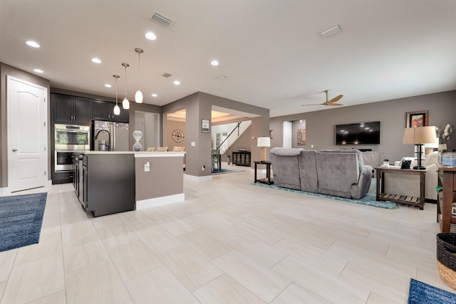 kitchen featuring a center island with sink, ceiling fan, hanging light fixtures, and appliances with stainless steel finishes