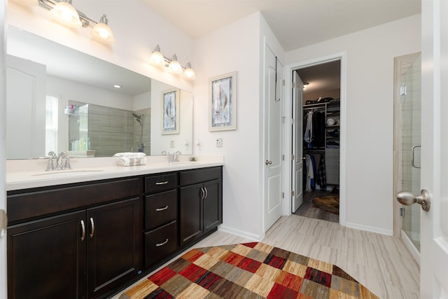 bathroom featuring a shower with door and vanity