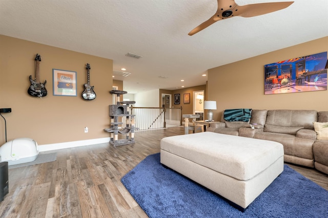 living room featuring ceiling fan, wood-type flooring, and a textured ceiling