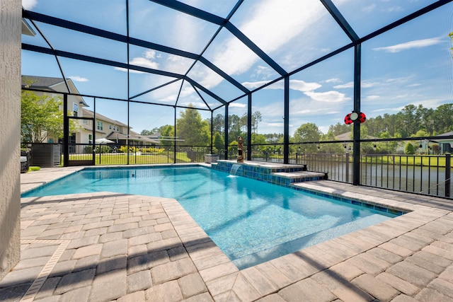 view of pool featuring pool water feature, glass enclosure, a water view, and a patio