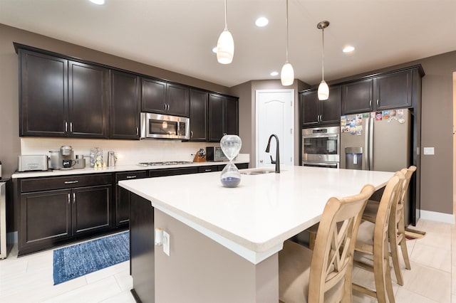 kitchen featuring hanging light fixtures, an island with sink, stainless steel appliances, and sink