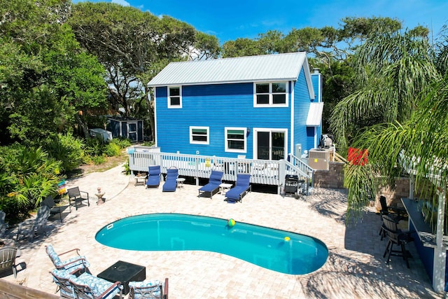 view of swimming pool with a wooden deck, a patio area, and an outbuilding