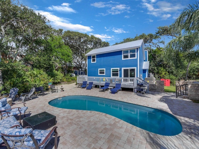 view of pool featuring a patio and a wooden deck