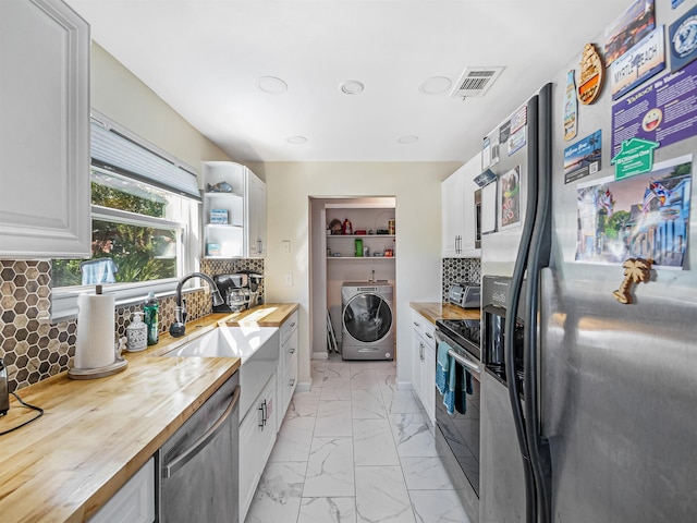 kitchen with white cabinetry, sink, wooden counters, washer / dryer, and appliances with stainless steel finishes