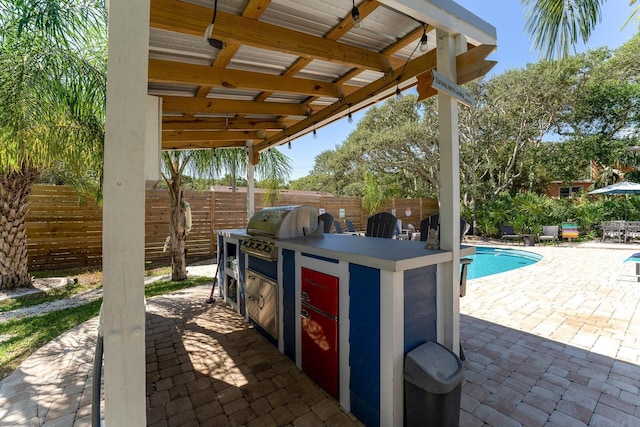 view of patio with a fenced in pool, a grill, and exterior kitchen