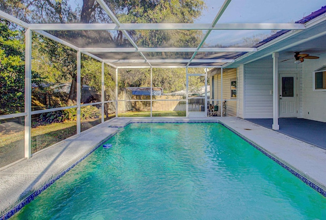 view of swimming pool with glass enclosure, ceiling fan, and a patio