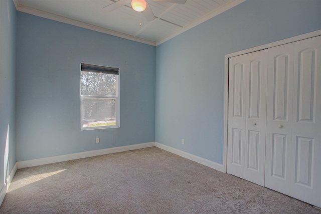 unfurnished bedroom featuring ceiling fan, light colored carpet, ornamental molding, and a closet