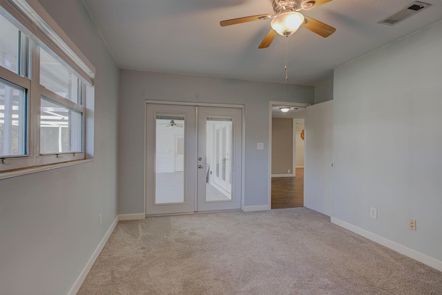 empty room featuring french doors, light colored carpet, and ceiling fan