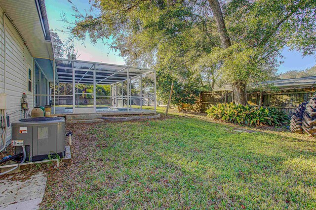 yard at dusk featuring glass enclosure, cooling unit, and a pool