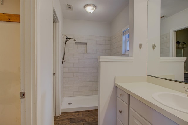 bathroom with a tile shower, vanity, and hardwood / wood-style flooring