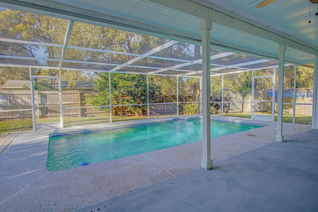 view of pool featuring glass enclosure, ceiling fan, and a patio