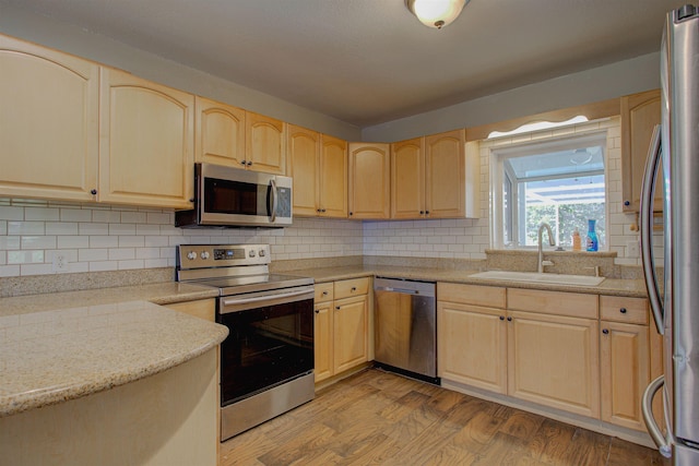 kitchen featuring sink, light hardwood / wood-style flooring, decorative backsplash, light brown cabinetry, and appliances with stainless steel finishes