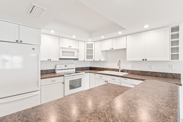 kitchen with white cabinets, white appliances, a raised ceiling, and sink