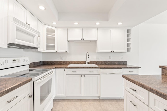 kitchen with sink, a raised ceiling, light tile patterned flooring, white appliances, and white cabinets