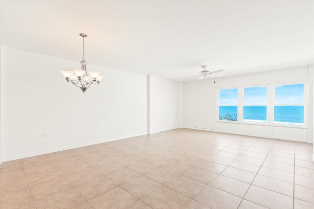 empty room with a textured ceiling, a water view, light tile patterned flooring, and ceiling fan with notable chandelier