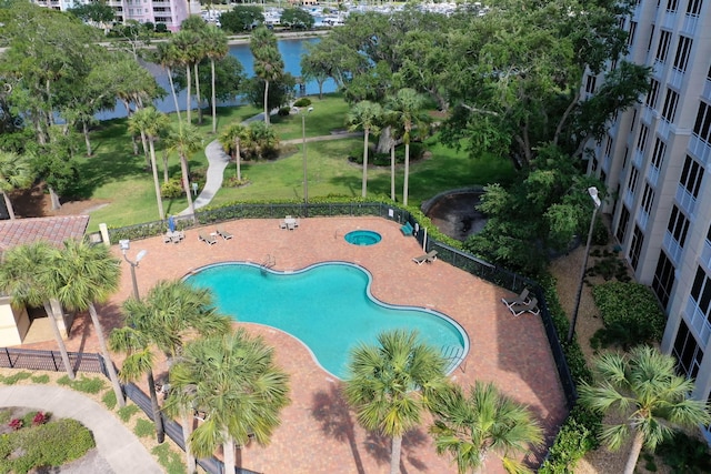 view of pool featuring a yard, a water view, and fence