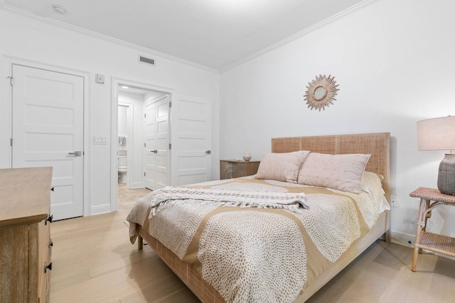 bedroom featuring baseboards, visible vents, connected bathroom, light wood-style flooring, and crown molding