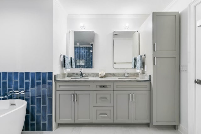 full bath featuring double vanity, a freestanding bath, ornamental molding, and a sink