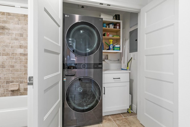 laundry room with cabinet space, electric panel, light tile patterned floors, and stacked washer / dryer