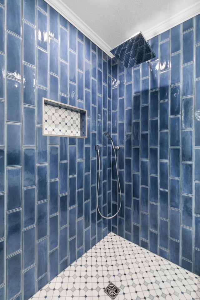 bathroom with ornamental molding and tiled shower