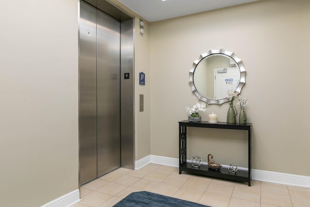 hall with light tile patterned floors, baseboards, and elevator