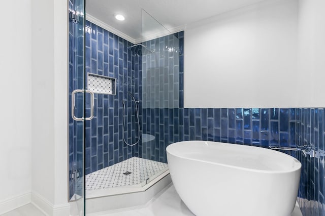 full bathroom with a stall shower, a freestanding tub, crown molding, and tile walls