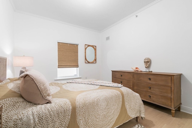 bedroom with ornamental molding, light wood-type flooring, visible vents, and baseboards