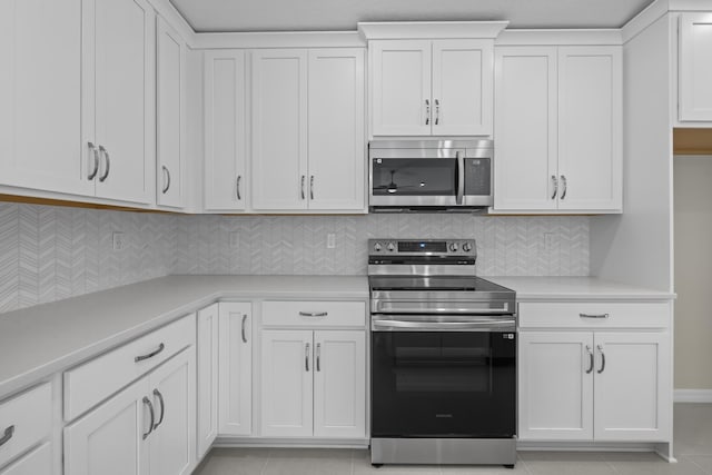 53 Pine Crest Ln, Palm Coast, FL 32164 - kitchen with appliances with stainless steel finishes, light countertops, white cabinets, light tile patterned floors, and decorative backsplash