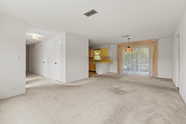 unfurnished living room with light carpet and a sink