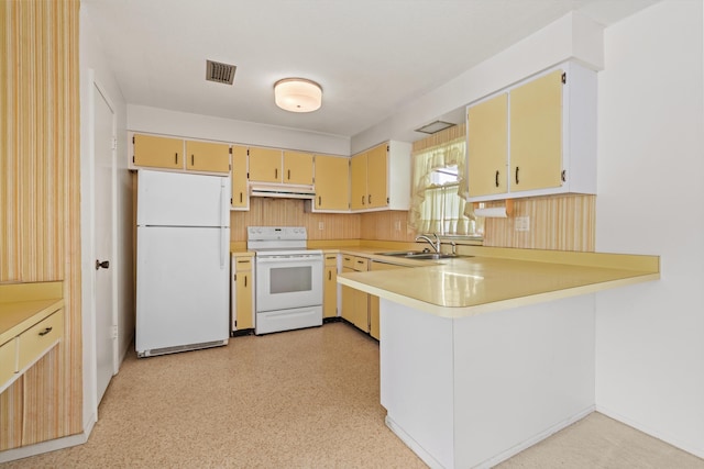 kitchen with white appliances, under cabinet range hood, a peninsula, light countertops, and a sink