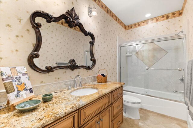 full bathroom featuring tile patterned floors, vanity, toilet, and bath / shower combo with glass door