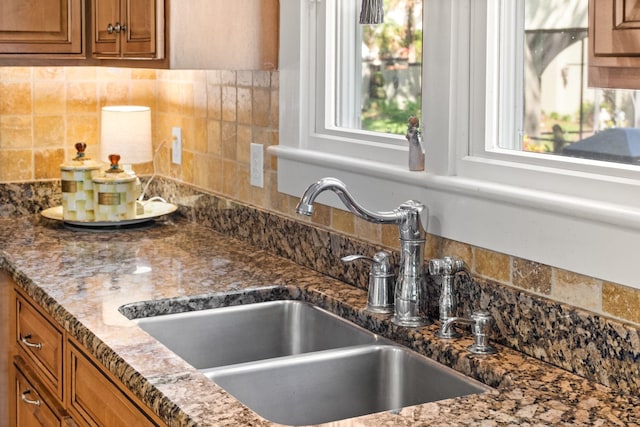 kitchen with tasteful backsplash, dark stone countertops, and sink