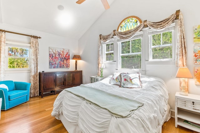 bedroom featuring multiple windows, ceiling fan, vaulted ceiling, and hardwood / wood-style flooring