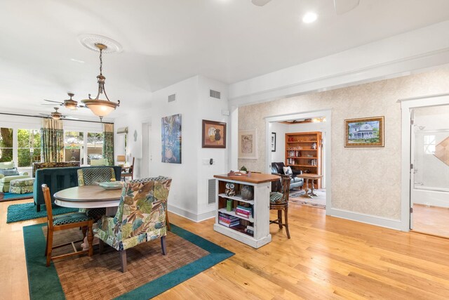 dining area with light wood-type flooring and ceiling fan