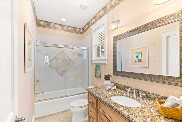 full bathroom featuring combined bath / shower with glass door, tile patterned floors, vanity, and toilet