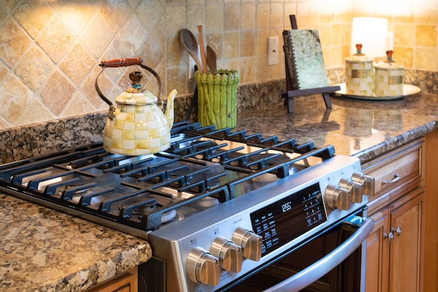 room details featuring high end stove, tasteful backsplash, and stone countertops