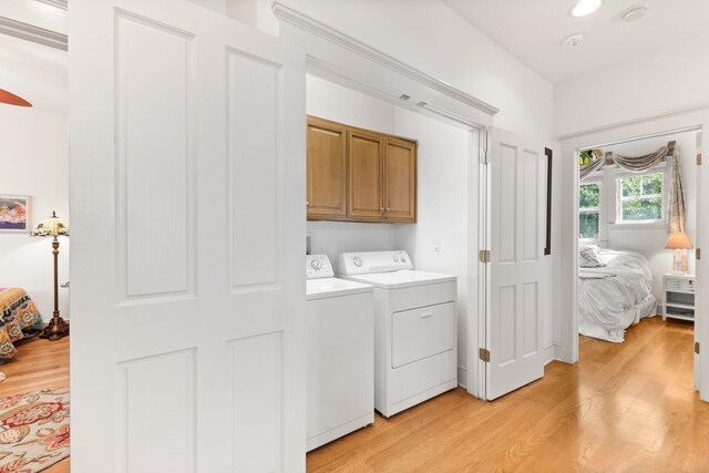 laundry room featuring cabinets, washing machine and dryer, and light hardwood / wood-style flooring