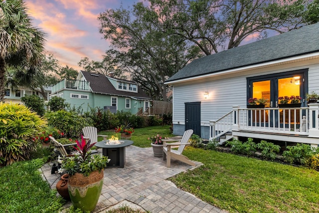 patio terrace at dusk featuring a lawn and an outdoor fire pit