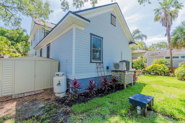 view of side of property featuring a lawn, ac unit, and a shed