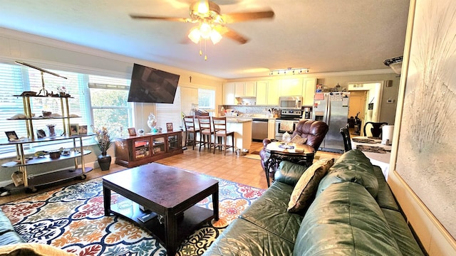 living room featuring ornamental molding, rail lighting, and ceiling fan