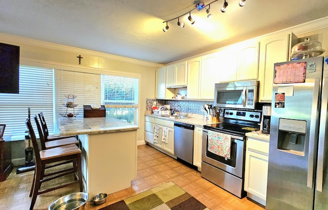 kitchen featuring light parquet flooring, appliances with stainless steel finishes, a kitchen breakfast bar, and white cabinets