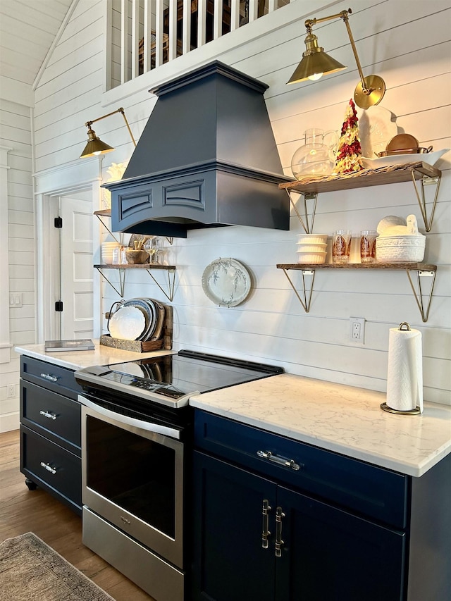 kitchen with stainless steel electric range, blue cabinets, custom exhaust hood, and vaulted ceiling