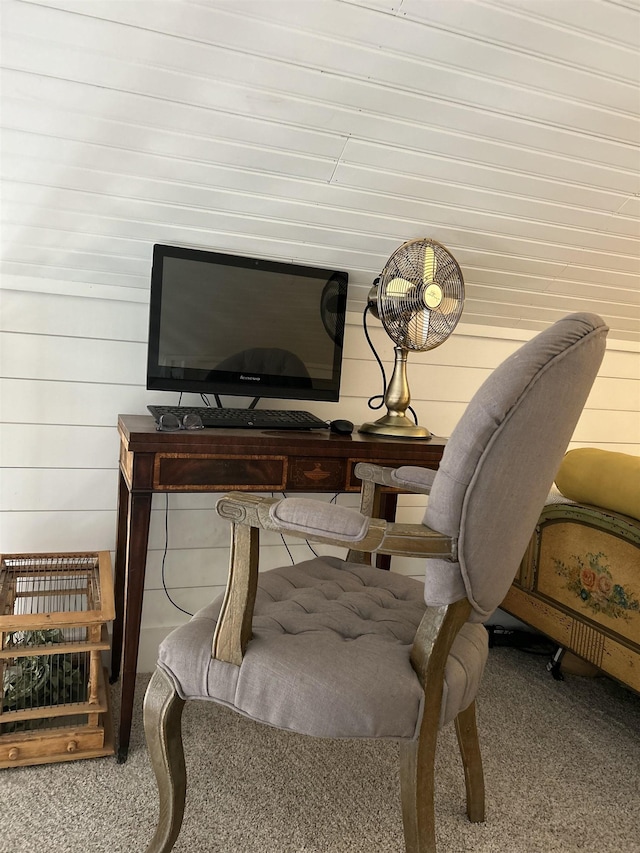 sitting room featuring carpet flooring and wood walls