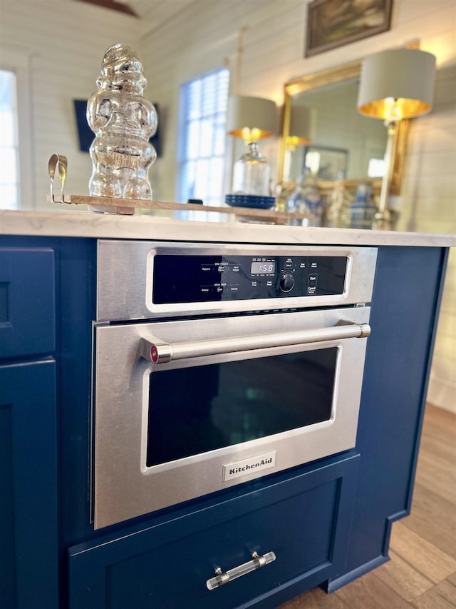 details with light hardwood / wood-style flooring, oven, and blue cabinets