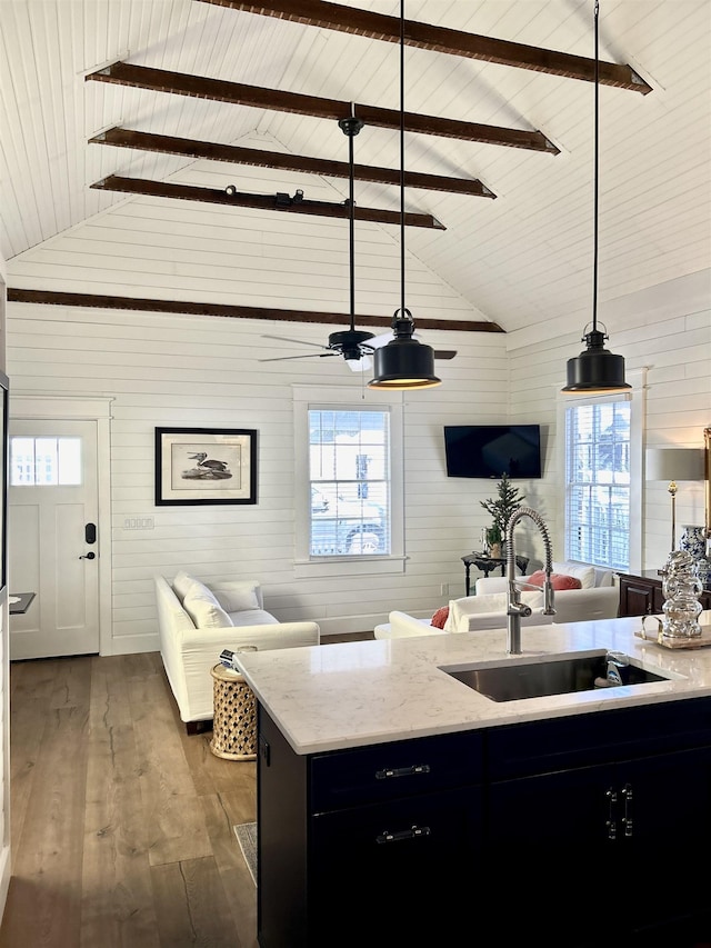 kitchen featuring sink, dark wood-type flooring, hanging light fixtures, high vaulted ceiling, and wood walls