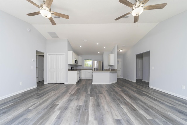 unfurnished living room featuring dark hardwood / wood-style floors, vaulted ceiling, and ceiling fan