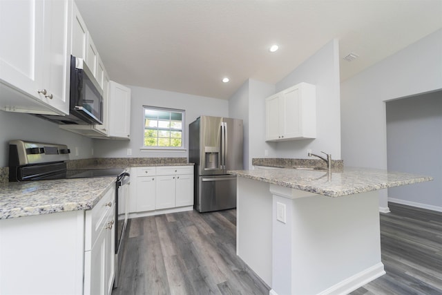 kitchen featuring dark wood-type flooring, an island with sink, lofted ceiling, white cabinets, and appliances with stainless steel finishes